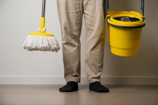 man-standing-holding-yellow-mop-bucket-cleaning