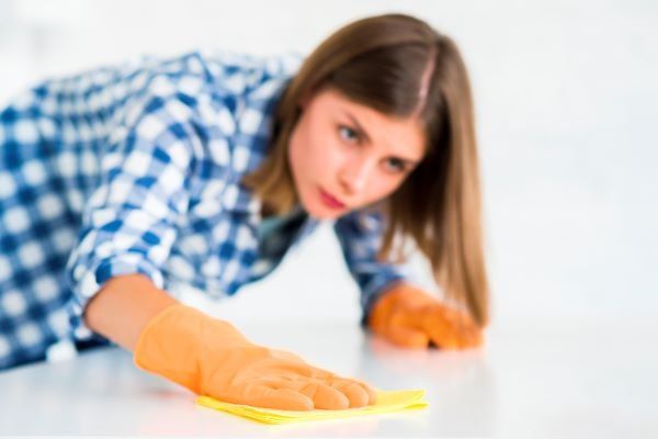 woman-cleaning-white-surface-yellow-wipes